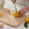 A person uses a knife to slice a lemon on a Large Classic Cutting and Serving Board. bambu