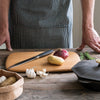 A large Classic Cutting & Serving Boards holds a potato and an onion. A bulb of garlic waits nearby.