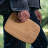 A person in blue jeans holds a bamboo bar board in their right hand.