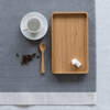 A Teaspoon and tea tray are displayed on a blue tablecloth with a white cup and saucer.