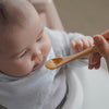 A young baby is fed applesauce from an Organic Bamboo Baby's Feeding Spoon (6M+)