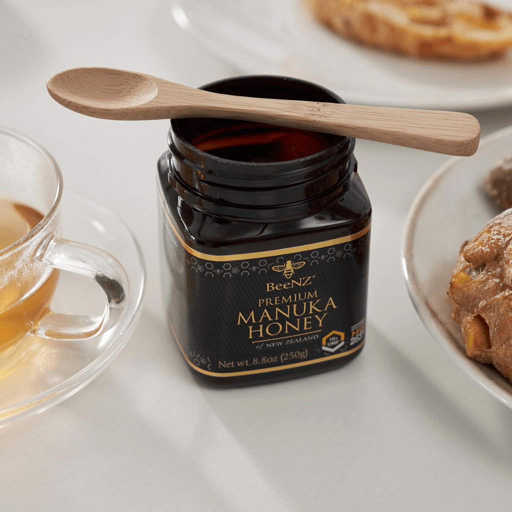 A bamboo teaspoon rests on a jar of Manuka Honey. bambu