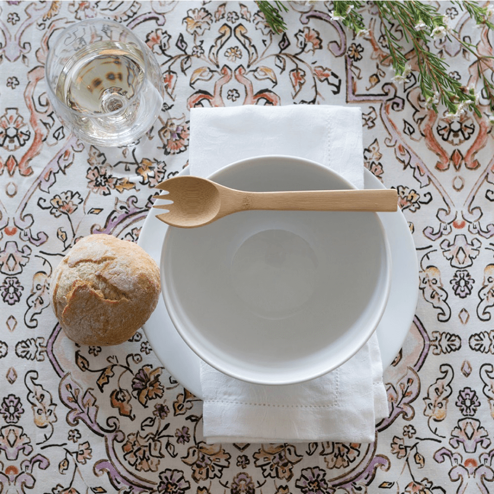 A Large Spork rests atop a white ceramic bowl, as part of a table setting