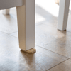 A Bamboo Tippy Table Wedge is under a wobbly table leg.