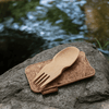 A Spork & Cork set lays on a rock next to a stream. Use this set in the outdoors