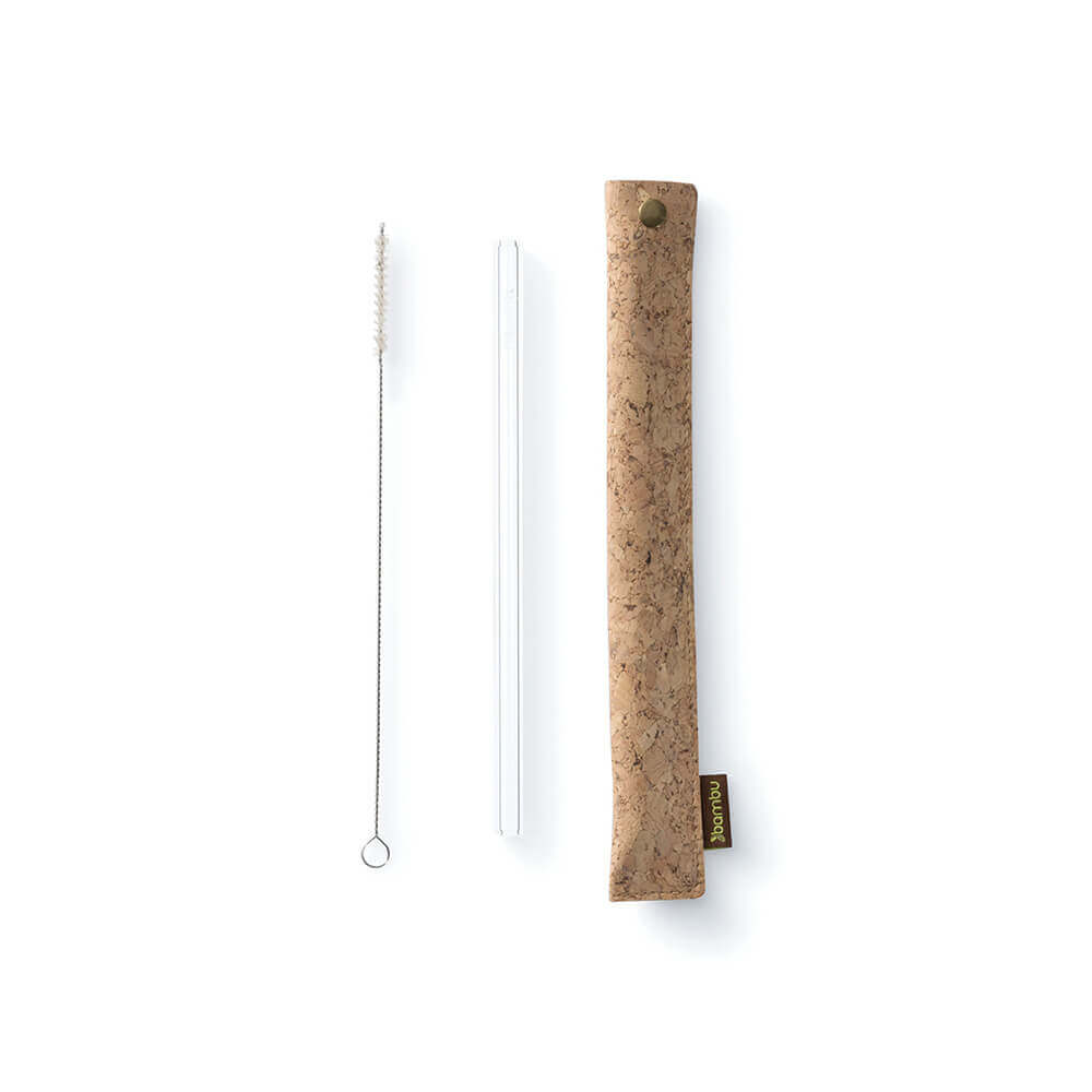 A cork fabric straw sleeve is displayed next to a glass straw and a straw cleaning brush.