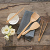 A bamboo Rice Paddle, wok spatula, small tongs, and chopsticks make up a collection of Asian cooking tools.