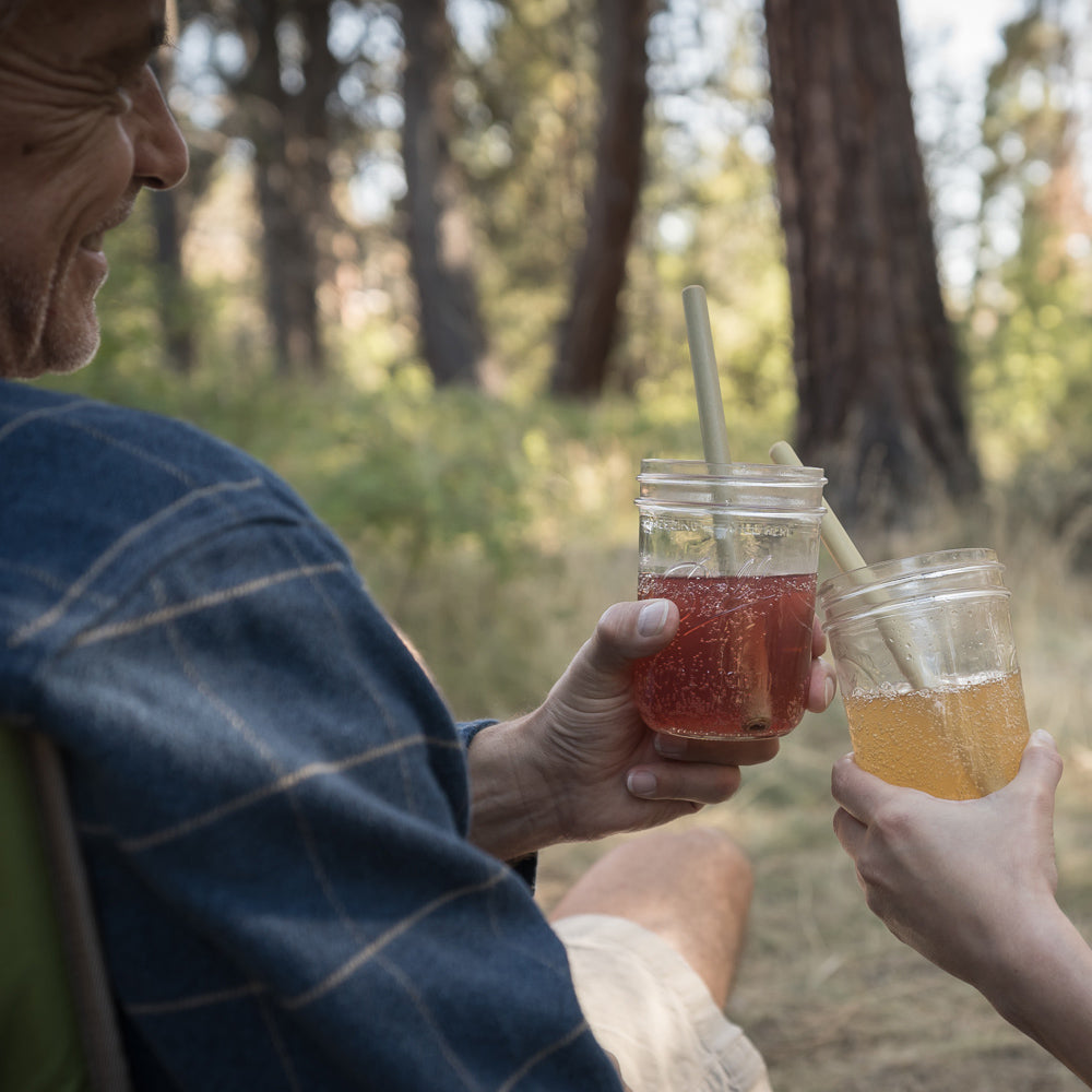 A pair of people "cheers" with beverages that have Reusable Bamboo straws in them. 