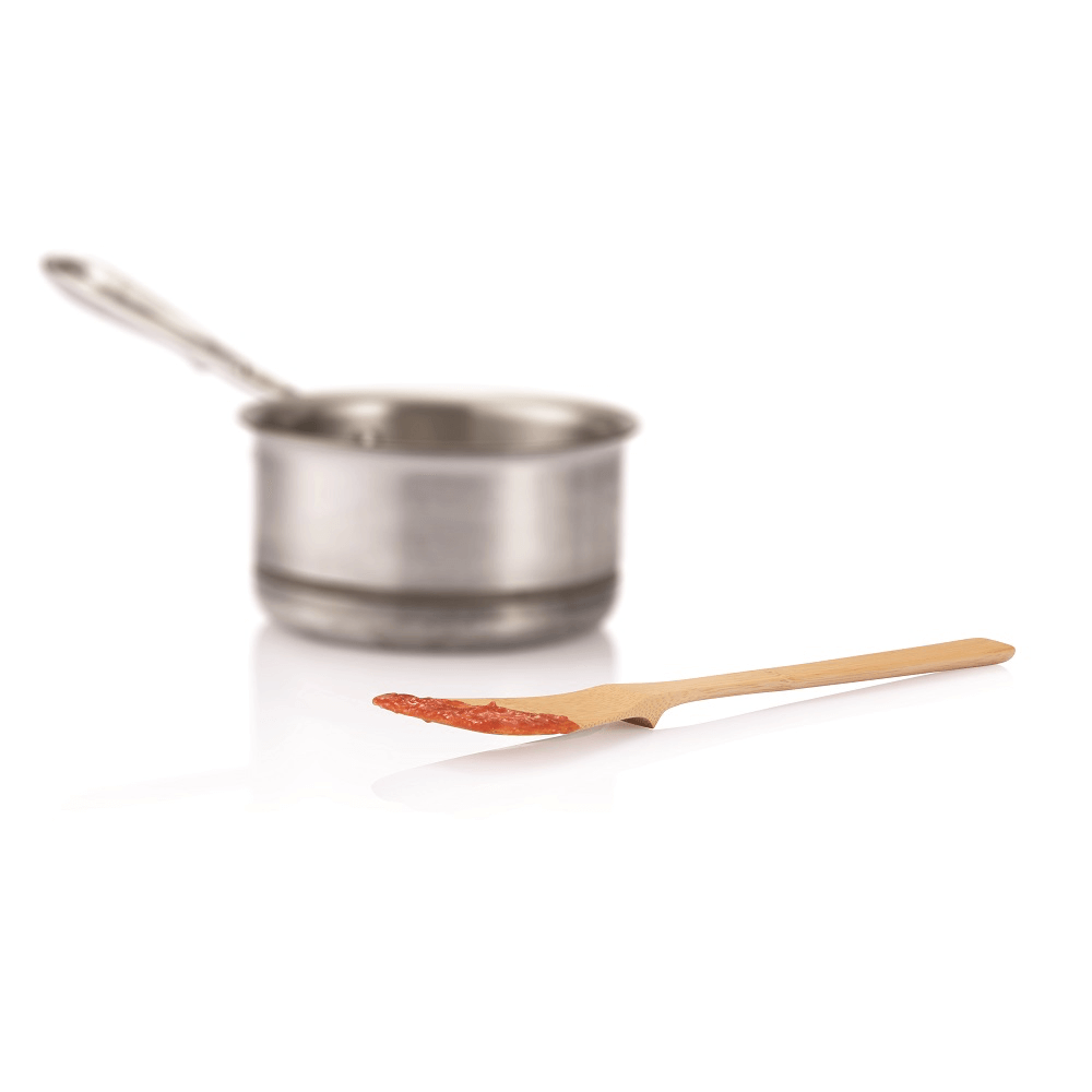 A 'Give It a Rest' Slotted Spoon with sauce on it is shown in front of a pot. The built in rest keeps sauce of counter.