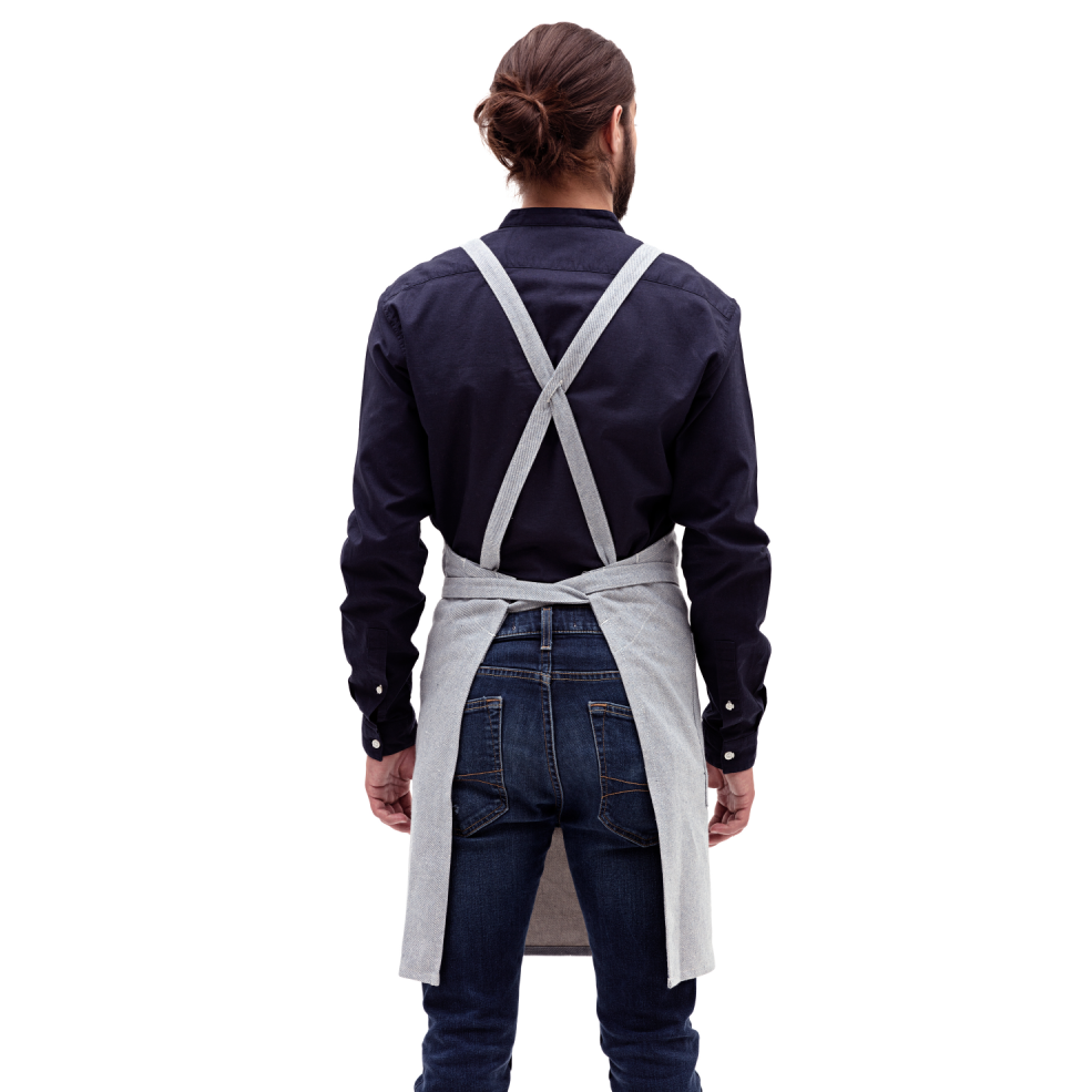A man wearing a MEEMA Crossback Apron made with Upcycled Denim highlights the fit from the back.