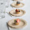 A trio of 7" Veneerware® Fancy Bamboo Plates are set on a table. Each plate has a small fruit tart.