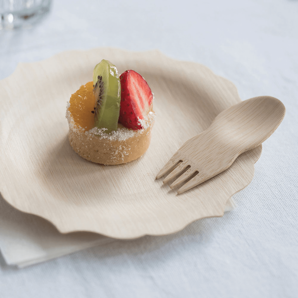 A Veneerware® Bamboo Spork is on a  dessert plate with a small fruit tart.