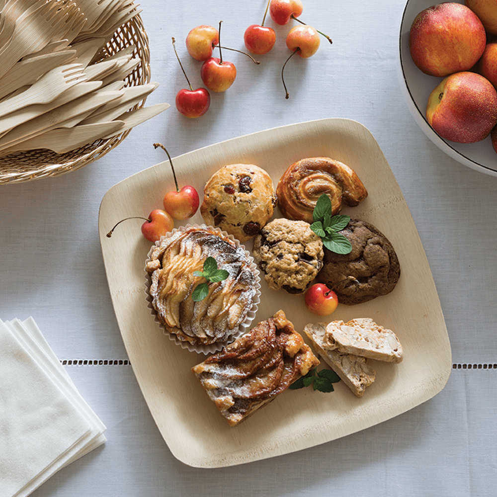 An 11" Veneerware® Square Bamboo Plates is loaded up with a variety of baked goods.